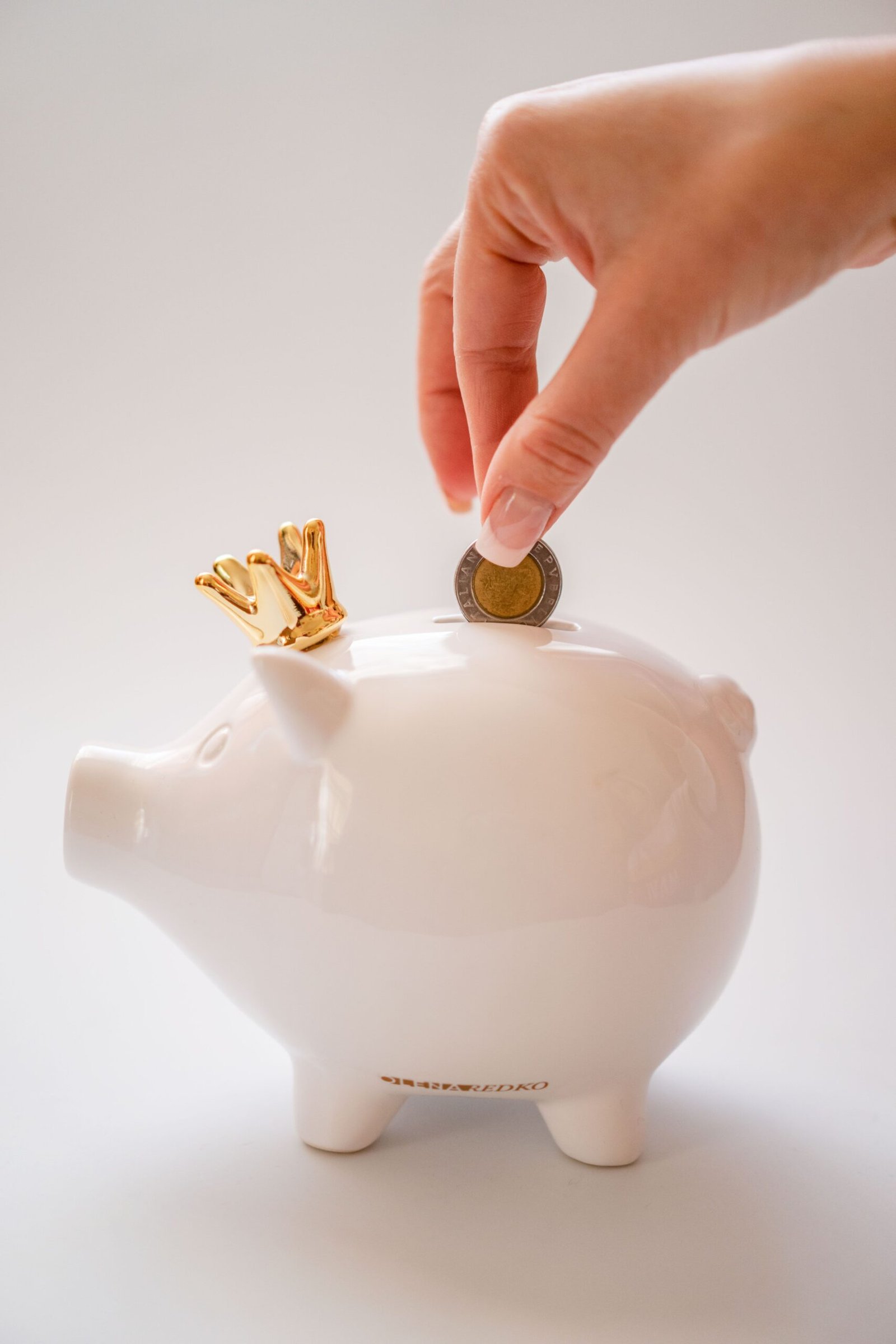 Hand putting a coin into a piggy bank to build emergency savings